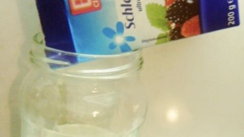 Eine Kartonverpackung mit Schlagsahne wird über ein Glas geschüttet, um abgelaufene Sahne in Butter zu verwandeln.