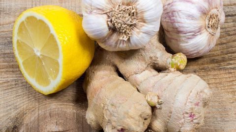 Ingwer, Knoblauch und Zitrone liegen auf einem Holztisch, bereit für die Nutzung in der Naturmedizin aus der Gewürz- und Gemüseabteilung.