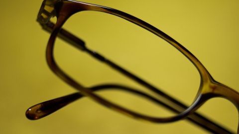 Eine Brille liegt auf einem gelben Hintergrund, während sie zum Putzen bereitsteht und darauf wartet, gereinigt zu werden.