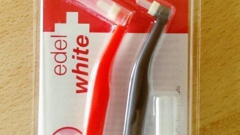 Einbüschelbürsten in einer Verpackung, zeigen zwei kleine Zahnbürsten in rot und schwarz für eine gezielte Zahnreinigung.