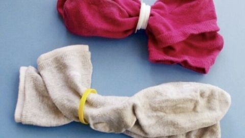 Zwei zusammengebundene Socken liegen auf einer blauen Oberfläche, wobei die bunte Socke eine Erklärung für das Verschwinden darstellt.