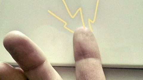 Ein Finger berührt eine Oberfläche, während gelbe Zickzacklinien statische elektrische Entladung symbolisieren.