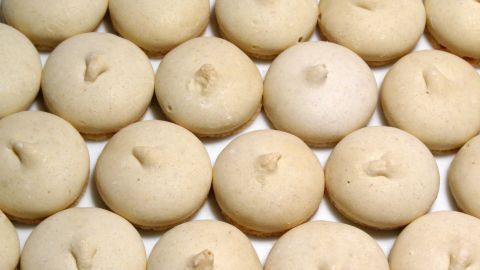 Deckelplätzchen sind gleichmäßig angeordnet, bereit zum Backen, mit glänzenden, leicht gewölbten Oberflächen in einem hellen Umfeld.