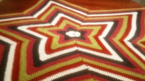 Eine bunte Sternform-Tischdecke liegt auf einem Holztisch, umgeben von einer gemütlichen, heimischen Atmosphäre.