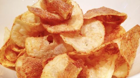Knusprige Kartoffelchips liegen in einer Schüssel, glänzend und frisch zubereitet, bereit zum Genießen.