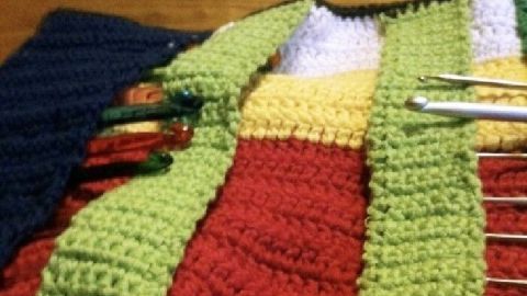 Ein bunt gehäkelter Utensilo für Häkelnadeln liegt auf einem Tisch, bereit zur Nutzung in einem gemütlichen Raum.