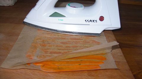 Karotten Chips werden mit dem Bügeleisen zwischen Backpapier gebügelt.