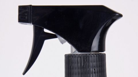 Eine schwarze Sprühflasche mit einem triggerartigen Sprühkopf steht vor einem neutralen Hintergrund, bereit für die Reinigung von Fliesen.