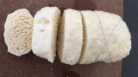 Böhmische Knödel liegen auf einem Holzbrett und sind in gleichmäßige Scheiben geschnitten für eine traditionelle Mahlzeit.