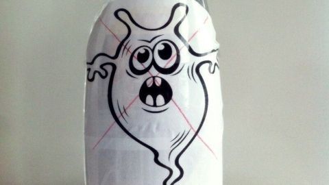 Ein Sprühflasche mit einem lustigen Monstersymbol stellt das Anti-Monster-Spray für Kinder dar, das in einem hellen Raum steht.