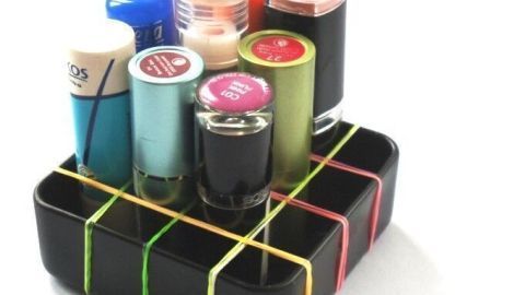 Eine Box mit Gummiband-Aufteilung hält verschiedenfarbige Fläschchen geordnet und stabilisiert sie in einem kompakten Raum.