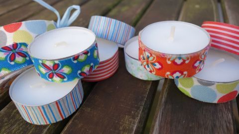 Bunte Teelichter liegen dekorativ auf einem Holzuntergrund, bereit, ausgelöscht oder angezündet zu werden.