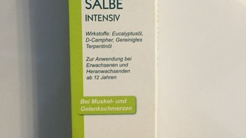 Eine Schmerz- und Rheumasalbe steht aufrecht in einer hellen Umgebung, unterstreicht ihre Nutzung bei Beschwerden.
