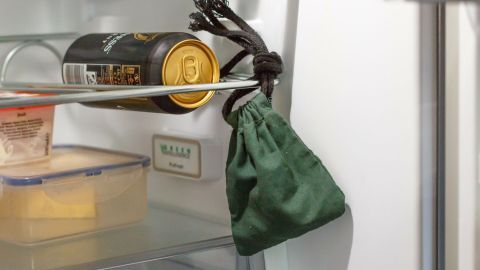 Multitalent Natron gegen unangenehme Gerüche im Kühlschrank. Ein grüner Beutel hängt in einem Kühlschrank, daneben eine Dose, die auf Gerüche im Kühlschrank hinweisen könnte.