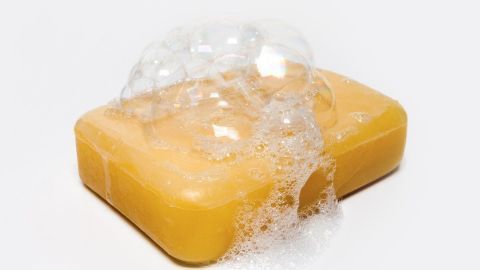 Eine gelbe Seife mit Blasen liegt auf einem weißen Untergrund und wirkt frisch, geeignet zum Entfernen von alten Blutflecken.