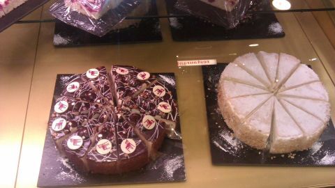 Zwei Kuchen liegen auf einem goldenen Tisch in einem Möbelhaus-Restaurant, verziert mit Schokolade und Früchten.