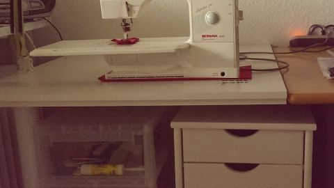 Eine Nähmaschine steht auf einem Tisch, während unter dem Tisch Platz für Kreativität genutzt wird.
