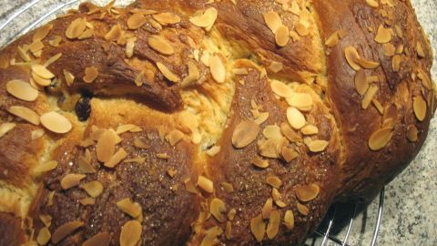 Ein goldbrauner Hefe-Rosinen-Zopf liegt auf einem Kuchengitter und strahlt frisches Gebäck-Aroma aus.