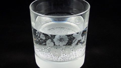 Ein transparentes Glas mit sprudelndem Wasser steht auf einem dunklen Hintergrund, ideal für mehr Trinken aus kleinen Gläsern.
