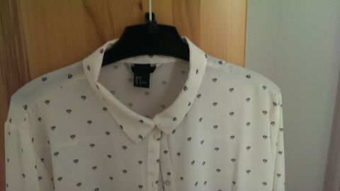 Mit Sprühstärke kannst du dünne Kragen auf eine elegante Weise betonen und ihnen mehr Struktur verleihen. Dieser Tipp hilft dir, jedes Outfit aufzuwerten und ein gepflegtes Erscheinungsbild zu erzielen. Ein weißes Hemd mit dünnem Kragen hängt an einem schwarzen Kleiderbügel vor einer Holzwand, bereit zum Sprühen mit Stärke.