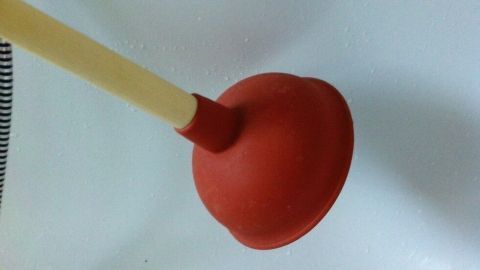 Eine Saugglocke liegt auf einer weißen Oberfläche, bereit, verwendet zu werden, um Verstopfungen zu reinigen.