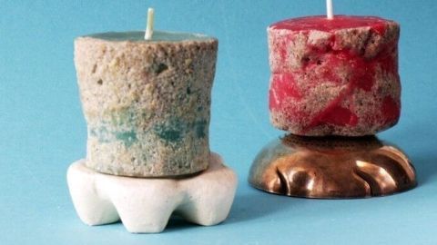 Bunte Sandkerzen stehen auf einem hellen Untergrund, während sie fröhlich im Licht leuchten und für Stimmung sorgen.