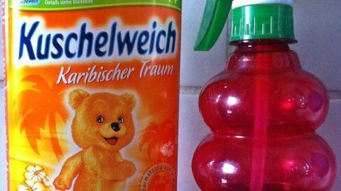 Eine Flasche Weichspüler steht neben einem Sprühbehälter, bereit zum Raumduft selber machen für ein angenehmes Aroma.