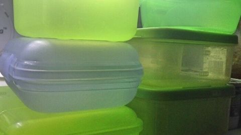 Stapelhaufen leuchtend grüner und transparenter Kühlschrankbehälter, der zur Aufbewahrung von Lebensmitteln genutzt wird.