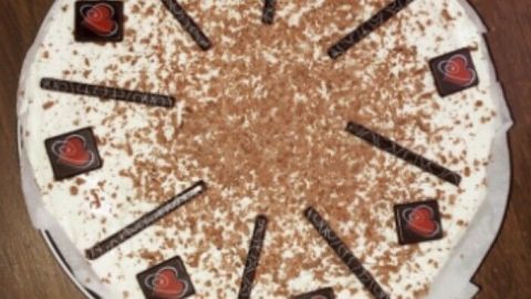 Eine köstliche Torte mit frischer Sahne, dekoriert mit Schokoladenstücken und Schokoladenraspeln, perfekt für einen Muttertag.