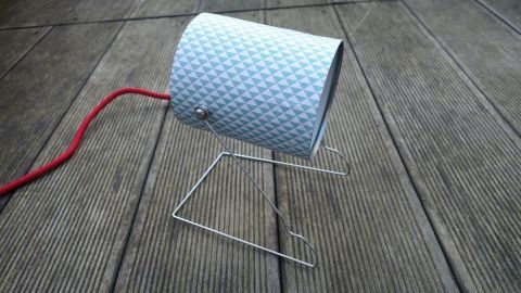 Eine Dosenlampe steht auf einem Tisch, während ein rotes Kabel herausführt und sie beleuchtet.