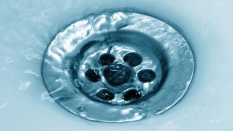 Der Abfluss ist mit Wasser gefüllt und es strömt um die Metallabdeckung, um Verstopfungen zu vermeiden.