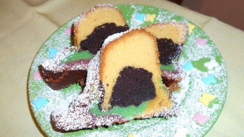 Auf einem bunten Teller liegt ein konfettibedeckter Papageienkuchen, dessen Stücke appetitlich angerichtet sind.