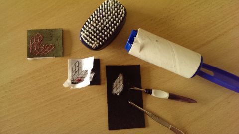 Eine Rolle mit klebrigem Band entfernt Stickvlies von einer schwarzen Karte, um es für kreative Projekte zu nutzen.