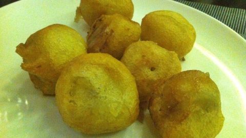 Die goldbraunen gebackenen Bananen liegen auf einem weißen Teller und wirken knusprig, ideal als Snack oder Dessert.
