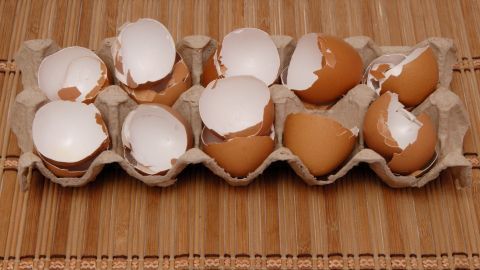 Eierschalen liegen auf einem Pappkarton und sind teilweise zerbrochen, bereit zur Herstellung von natürlichem Kalzium.