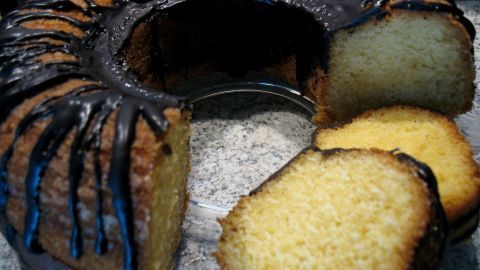 Ein saftiger, glutenfreier Vanille-Gugelhupf wird angeschnitten, während er auf einem Teller präsentiert wird, umgeben von einer geselligen Atmosphäre.