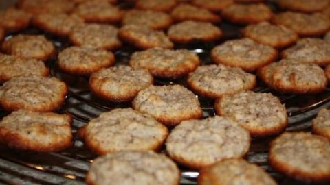 Makronen kühlen auf einem Gitter ab und sind goldbraun gebacken. Sie liegen eng zusammen und wirken frisch zubereitet.