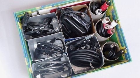 Kabel sind ordentlich in einem bunten Behälter und Papprollen aufbewahrt, um Ordnung im Raum zu schaffen.