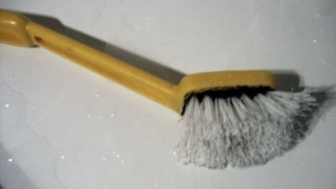 Eine verschmutzte Spülbürste liegt auf einer glatten, sauberen Oberfläche und wartet darauf, gereinigt zu werden.