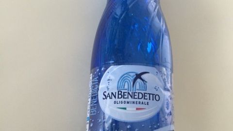Eine blaue Flasche mit Mineralwasser steht auf einem Tisch und könnte als improvisierter Kühlakku verwendet werden.