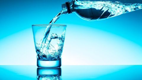 Ein Glas wird mit klarem Wasser aus einer Flasche gefüllt, um das richtige Trinken zu fördern.