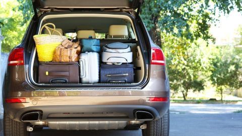 Der Kofferraum eines Autos ist geöffnet und enthält gepackte Koffer und einen Korb, um für eine Reise bereit zu sein.