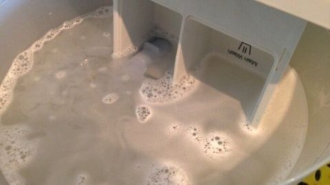 Ein Spülfach der Waschmaschine ist mit schaumigem Wasser gefüllt, während es gereinigt wird.