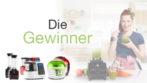 Eine Frau in einer Küche hält ein Glas mit einem grünen Getränk und zeigt auf die Wortmarke "Die Gewinner" neben verschiedenen Küchengeräten.