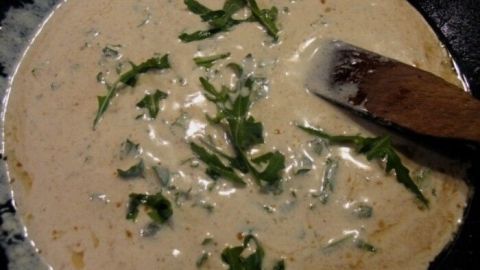 Eine cremige Chicorée-Suppe mit frischem Rucola wird in einer Schüssel angerichtet, bereit zum Servieren.