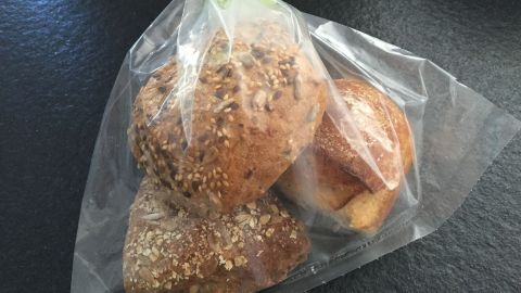 Frische Brötchen liegen in einem transparenten Beutel, bereit zum Verzehr auf einer dunklen Fläche.