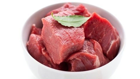 Der weiße Schüssel enthält rohe Fleischstücke, während eine Zwiebel und Gewürze in der Nähe liegen, bereit für die Zubereitung von Mock Turtle Soup.