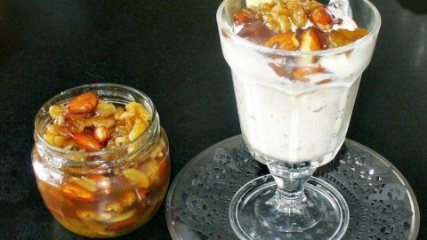 Geröstete Nüsse sind in einer Dessertschüssel mit Honig und einer Eisschicht, serviert auf einem eleganten Teller.