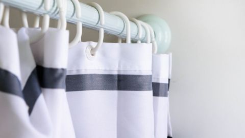 Ein Duschvorhang hängt an einem Stange mit weißen und schwarzen Streifen und ist in einem hellen Badezimmer platziert.