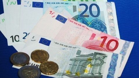 Buntes Geld liegt auf einem blauen Untergrund, das zeigt den Kontext, in dem man mit Online-Texten Geld verdienen kann.